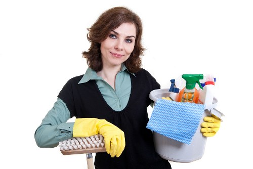 Cleaner using proper manual handling and slip prevention methods during a cleaning job.